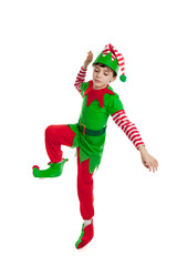 Full length portrait of an adorable 10 year old boy dressed in a Christmas elf costume dancing, isolated on a white background