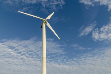 Wall Mural - Wind turbine in rotation to generate electricity outdoors with blue sky and clouds.