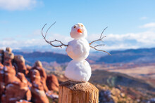 Tiny Snowman On Wooden Post. Blurred Fiery Furnace Sandstone Landscape Scenery In Arches National Park.