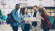 © silverkblack - Multiracial group of tourists is looking at paper map standing in the street in modern city talking and laughing. Travelling, navigation and wanderlust youth concept.
