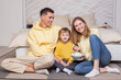 © artmim - Laughing smiling parents with child son sitting by the bed and eating popcorn