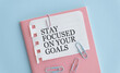 stay focused on your goals text on notebook and pen.