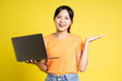 © STOCK88PHOTOGRAPHER - image of asian girl holding laptop and isolated on yellow background