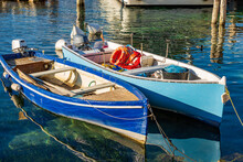 Closeup Of Two Small Wooden Fishing Boats Moored In The Small Port Of The Malcesine Village, Tourist Resort On The Coast Of Lake Garda. Verona Province, Veneto, Italy, Southern Europe.