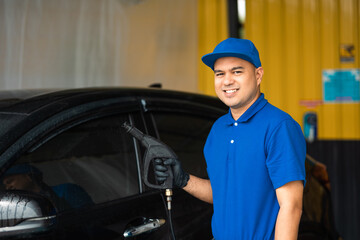 Wall Mural - Man worker washing car service. Car wash cleaning station high pressure water. Employees clean a vehicle professionally.