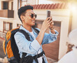 Happy man tourist taking a selfie with phone on vacation, holiday or travel for online social media in summer. Asian male using mobile smartphone in a foreign urban city or town with a smile outdoor