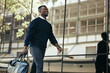 Fashion, travel and corporate employee or businessman traveling and walking out of a building or airport in a city. African American worker or traveler in an urban town with good style going to hotel