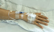 Close up patient with saline tube and intravenous catheter for injection plug in hand at hospital