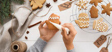 Woman decorating Christmas gingerbread cookies at table, top view