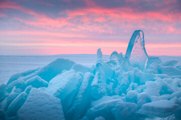 Wall Mural - Blue transparent ice on Baikal lake at sunrise. Pink clouds and blue ice with snow.