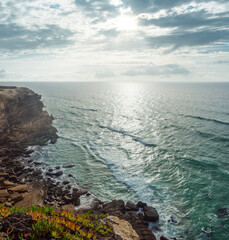 Wall Mural - rocky coastline, ocean and sunlight shines through gaps in clouds. beautiful nature background.