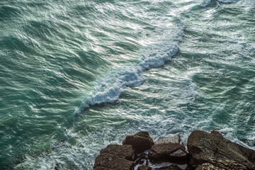 Wall Mural - ocean waves approaching rocky shore. top view.