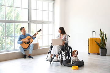 Sticker - Young man playing guitar for his wife in wheelchair and dog in their new flat on moving day