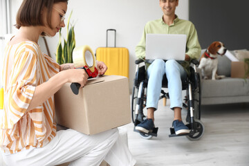 Sticker - Young woman taping moving box in room on moving day, closeup