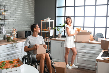 Wall Mural - Young woman and her husband in wheelchair in kitchen on moving day