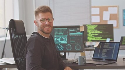 medium portrait of caucasian male programmer in eyeglasses turning to camera and starting smiling, s