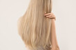 © Pixel-Shot - Woman touching blonde hair on light background