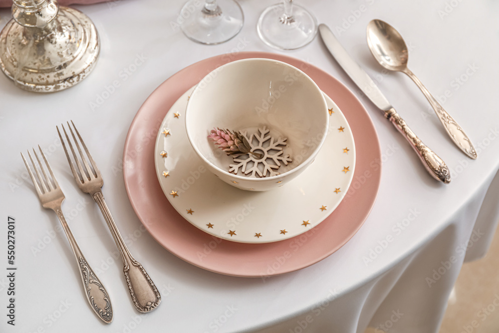 Christmas table setting with pink and white plates in dining room, closeup