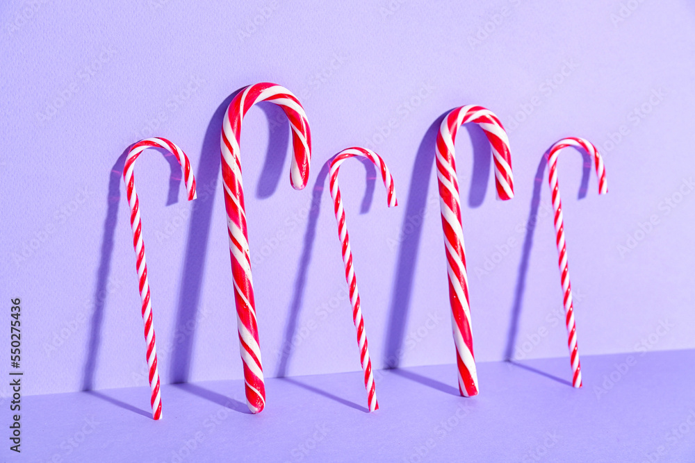 Sweet candy canes on lilac background