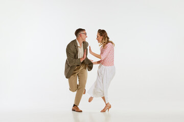 Wall Mural - Young excited man and woman in 60s american fashion style clothes dancing retro dance isolated on white background. Music, energy, happiness, mood, action