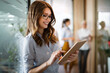 © NDABCREATIVITY - Young happy business woman working with tablet in corporate office