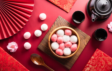 Tang Yuan(sweet dumplings balls), a traditional cuisine for Mid-autumn, Dongzhi (winter solstice ) and Chinese new year with plum flower and tea on red background.