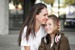 Mother hugs with daughter schoolgirl outdoors. Cheerful teen and female in good mood. Love and family concept