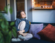 © olezzo - Young adult happy cheerful woman in warm sweater sitting on sofa enjoying resting and relaxing with her eyes closed