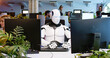 © ihorvsn - White robot sitting at table in office and typing on keyboard. Artificial intelligence working at computer in coworking space. Humanoid IT worker. Call center. Futuristic employee texting. Technology.