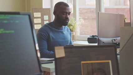 Serious African American computer expert program coding on desktop computer while working in office