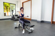 © ALEXEY - An adult brunette is engaged with dumbbells in the gym.