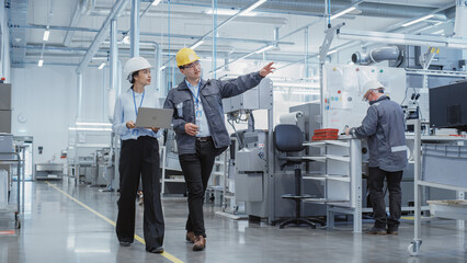 Aufkleber - Wide Shot: Two Heavy Industry Employees in Hard Hats Discussing Job Assignments at the Factory, Using Laptop Computer. Asian Engineer and Technician at Work Smiling