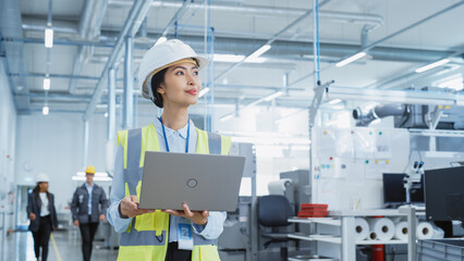 Fototapete - A Happy and Smiling Asian Female Engineer in White Hard Hat Standing with Laptop Computer at Electronic Manufacturing Factory. Successful Employee Watching the Work Flow