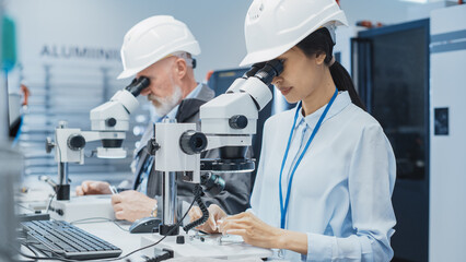 Poster - Modern Technology Concept: Two Scientists Examining Small Scale Industrial Equipment Parts Through a Microscope. Technicians Testing New Factory Components for Quality.