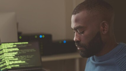 African American software engineer working on computer in server room at night, typing program codes