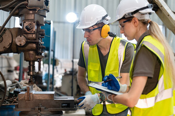 Male and female engineers in safety vest with helmet checking and repairing drilling machines at factory Industrial. Preventive Maintenance concept