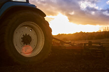 Tractor Working In Field At Sunset