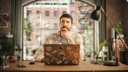 Poster - Professional Creative Man Sitting at a Desk at Home Office Studio, Working on Laptop Computer. Specialist Thinking About a Good Email Reply. Male Employee Working from Home Looking for Inspiration