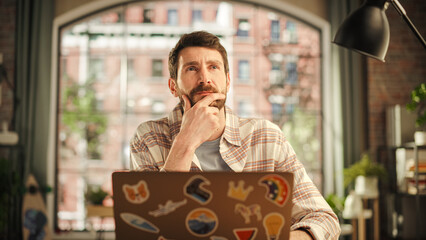 Poster - Professional Creative Man Sitting at a Desk at Home Office Studio, Working on Laptop Computer. Specialist Thinking About a Good Email Reply. Male Employee Working from Home Looking for Inspiration