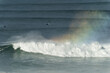 Big giant waves crashing in Nazare, Portugal creating a rainbow in the ocean. Surfers and jet skis in the water. Biggest waves in the world. Touristic destination for surfing.