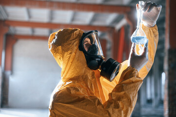 Examining radioactive liquid. Man dressed in chemical protection suit in the ruins of the post apocalyptic building