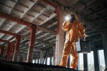 Wall Mural - Bottom view. Man dressed in chemical protection suit in the ruins of the post apocalyptic building