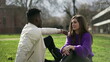 © Marco - Multi-cultural friends talking outside sitting on grass inc onversation
