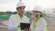 © Pixza - Two civil engineer work inspecting architect drawing on tablet at construction site.