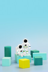 Wall Mural - Plastic figurines of astronauts in spacesuit and geometric shapes on blue background. Children's toys astronauts. Fascination with space, study of planets. Space to insert logo or promotional message