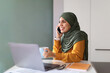 © Prostock-studio - Muslim Woman Talking On Cellphone And Drinking Coffee At Workplace In Office