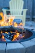 Vertical shot of a stone fire pit on a fall day with a white garden chair in the blur background
