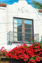 Clear Window With Metal Decorative Balcony On White Stucco Facade In Downtown San Francisco Neighborhood In California With Red Flowers