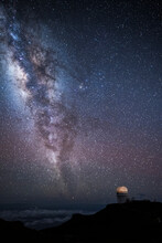 The Milky Way And Stars At Night Over The Observatory At Mt. Haleakala In Maui, Hawaii With Clouds Below.
