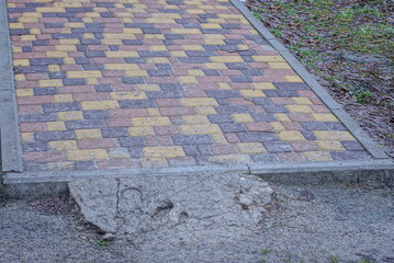 Poster - part of a sidewalk alley made of brown stone paving slabs on gray ground outdoors